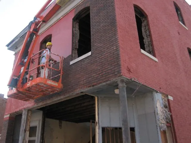 Worker in an orange lift working on the upper floor of a brick building