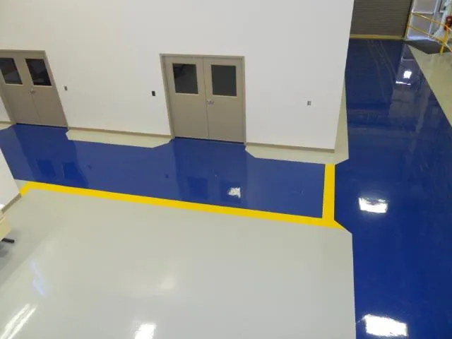 Glossy gray and blue epoxy floor with yellow safety striping
