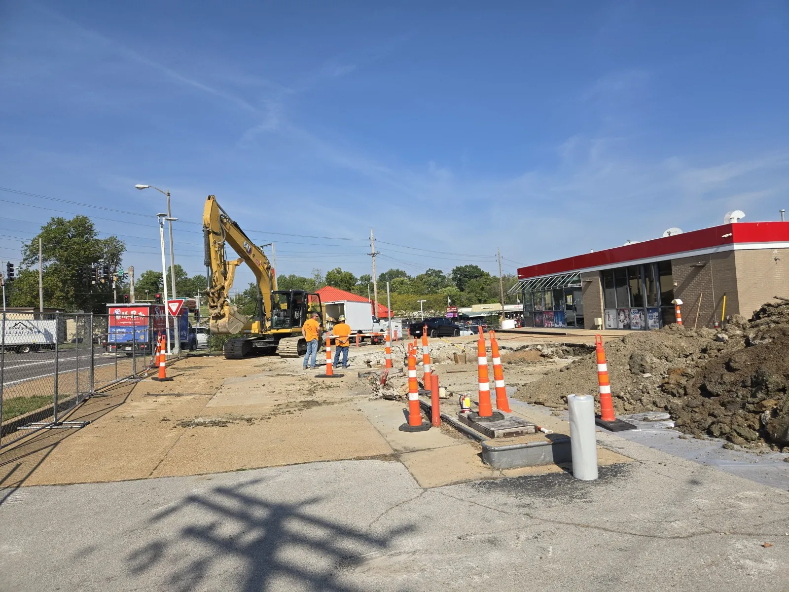 Excavator and crew behind traffic cones at a gas station tank removal